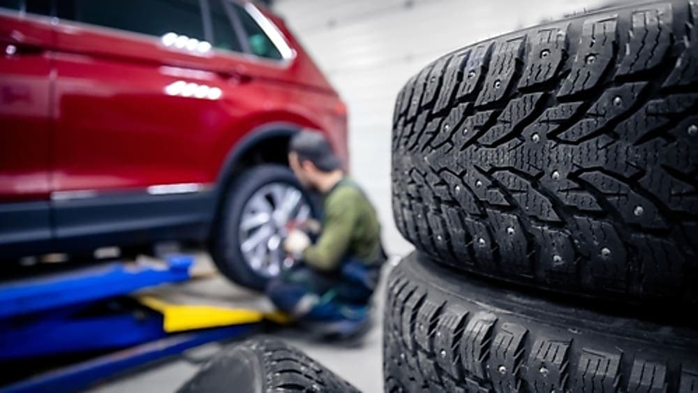 Mechanic changing tires in the background, with a close-up of the fresh tires.